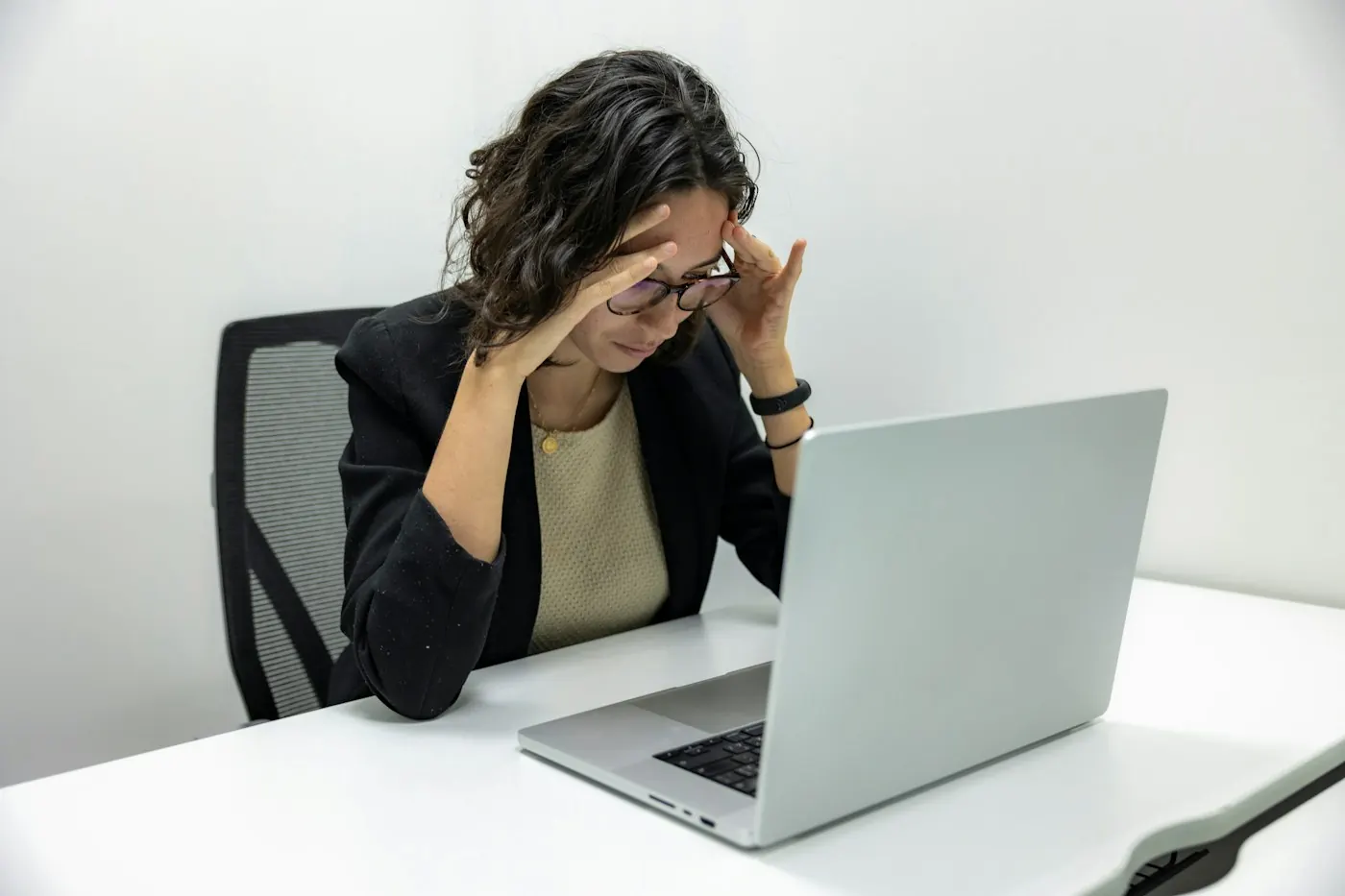 Woman at a laptop rubbing her temples from eye strain